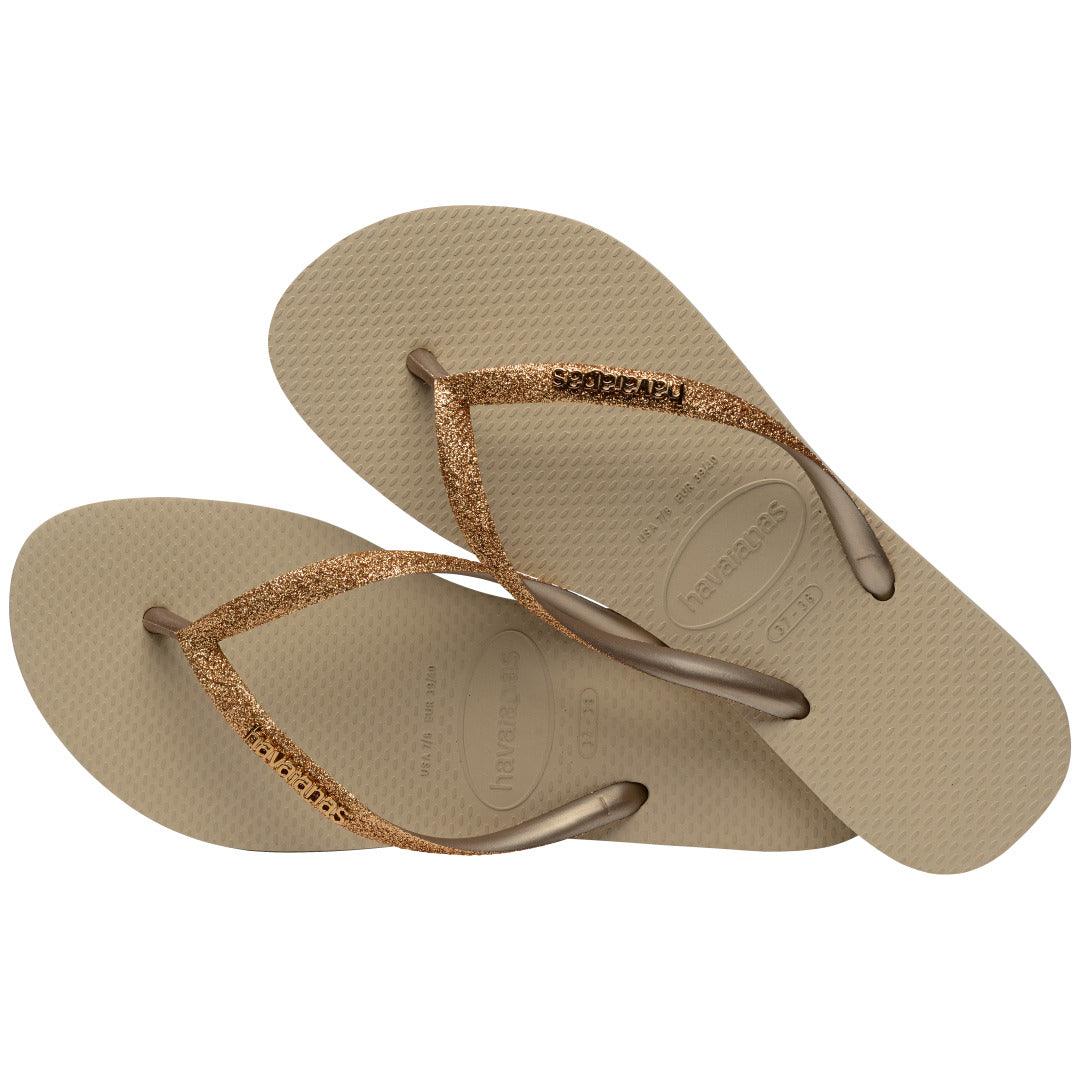 Chinelos Havaianas Slim Glitter II em composição cruzada, destacando o brilho das tiras e o solado areia texturizado.